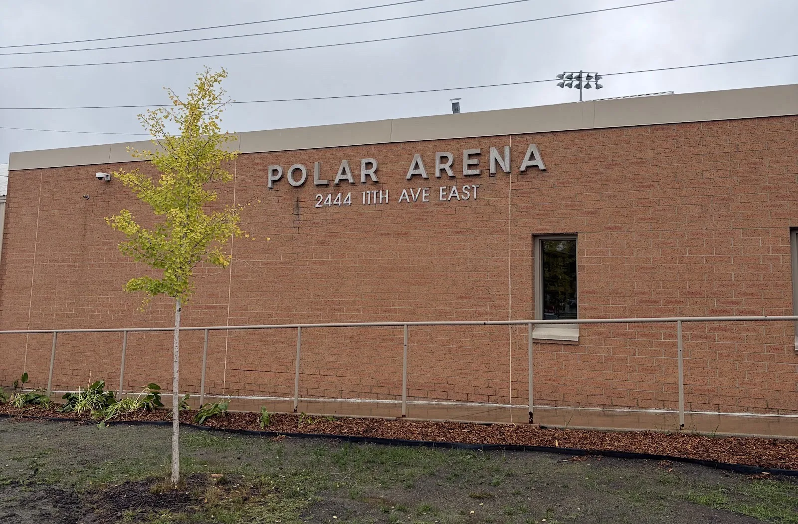 El muro de ladrillo de Polar Arena en North St. Paul, con su nombre y 2444 11th Ave East en letras sobre una nueva jardinera — Polar Arena (ISD 622)