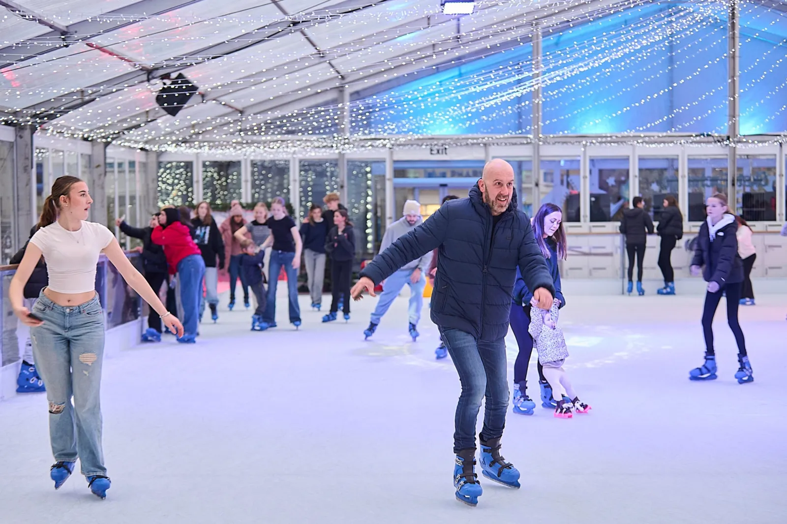 Skaters of all ages gliding on the Portsmouth on Ice rink under the clear tented roof hung with fairy lights. — Portsmouth On Ice