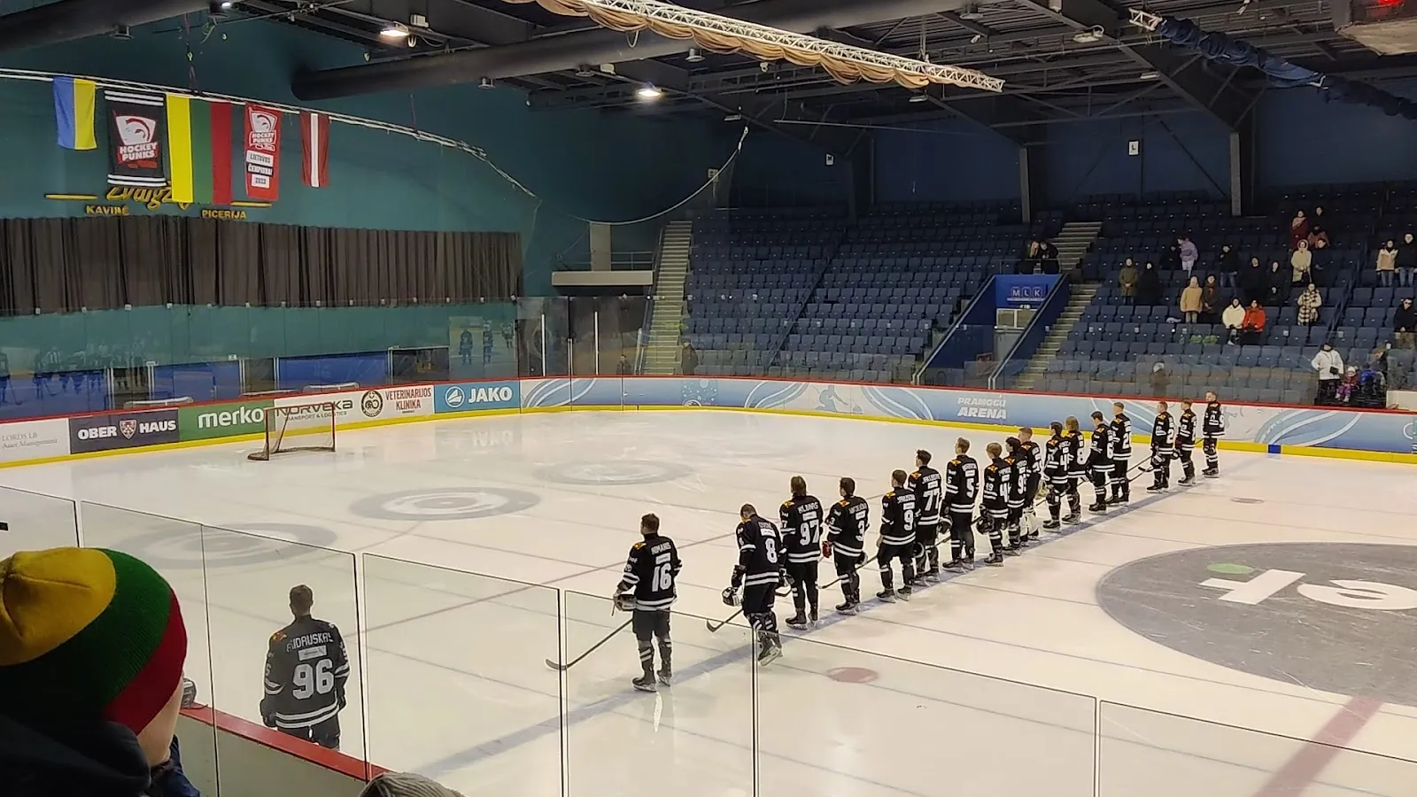 Vilniaus Pramogų arenos ledas, žaidėjai išsirikiavę palei liniją, o už bortų matyti tribūnos. – Pramogų Arena