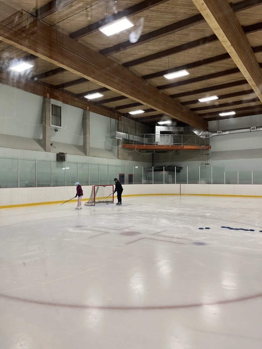 Priest Valley Arena ice with distant skaters under the timber roof — Priest Valley Arena