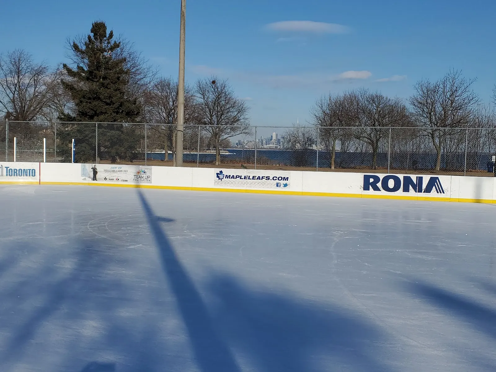 El hielo y las bardas con patrocinadores de la pista de Prince of Wales Park en un día soleado de invierno, sin personas a la vista — Prince Of Wales Park Outdoor Ice Rink