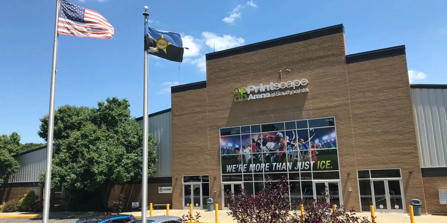 Printscape Arena's main entrance with its arena name above the glass doors and flags outside. — Printscape Arena at Southpointe