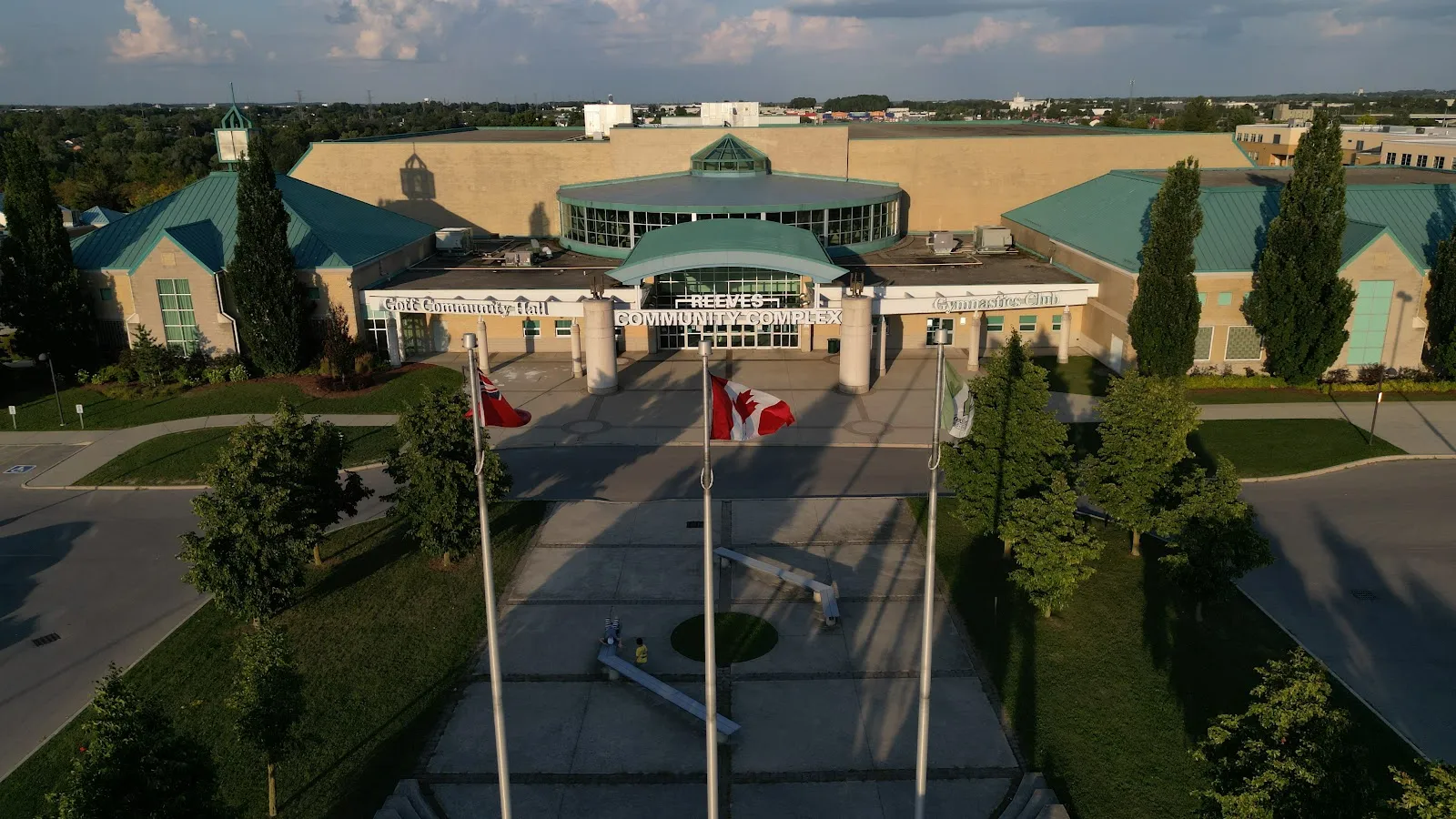 Aerial view of the Reeves Community Complex entrance, with its teal roofs, glass entry and flagpoles in front. — Reeves Community Complex (Southwood Arena)
