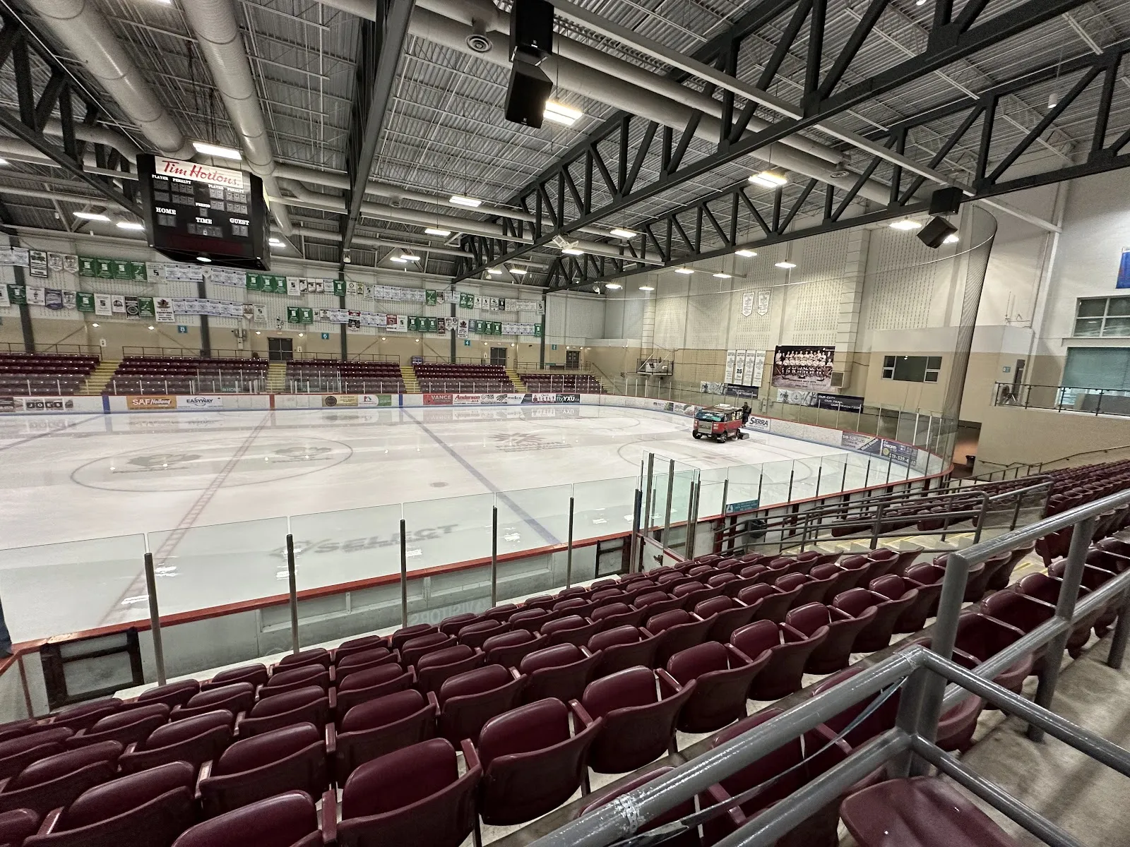 The empty ice from the maroon seats along the side, with the scoreboard and banners overhead. — Reeves Community Complex (Southwood Arena)