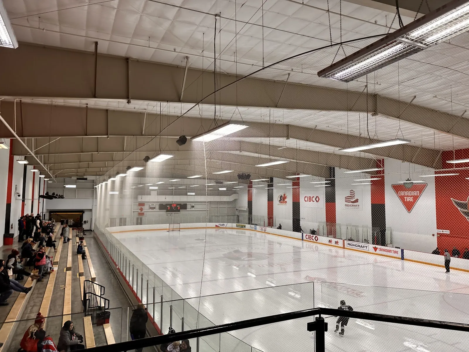 Toda la pista vista desde el pasillo superior durante un partido juvenil, con letreros de CIBC, Richcraft y Canadian Tire en la pared del fondo. — Richcraft Sensplex