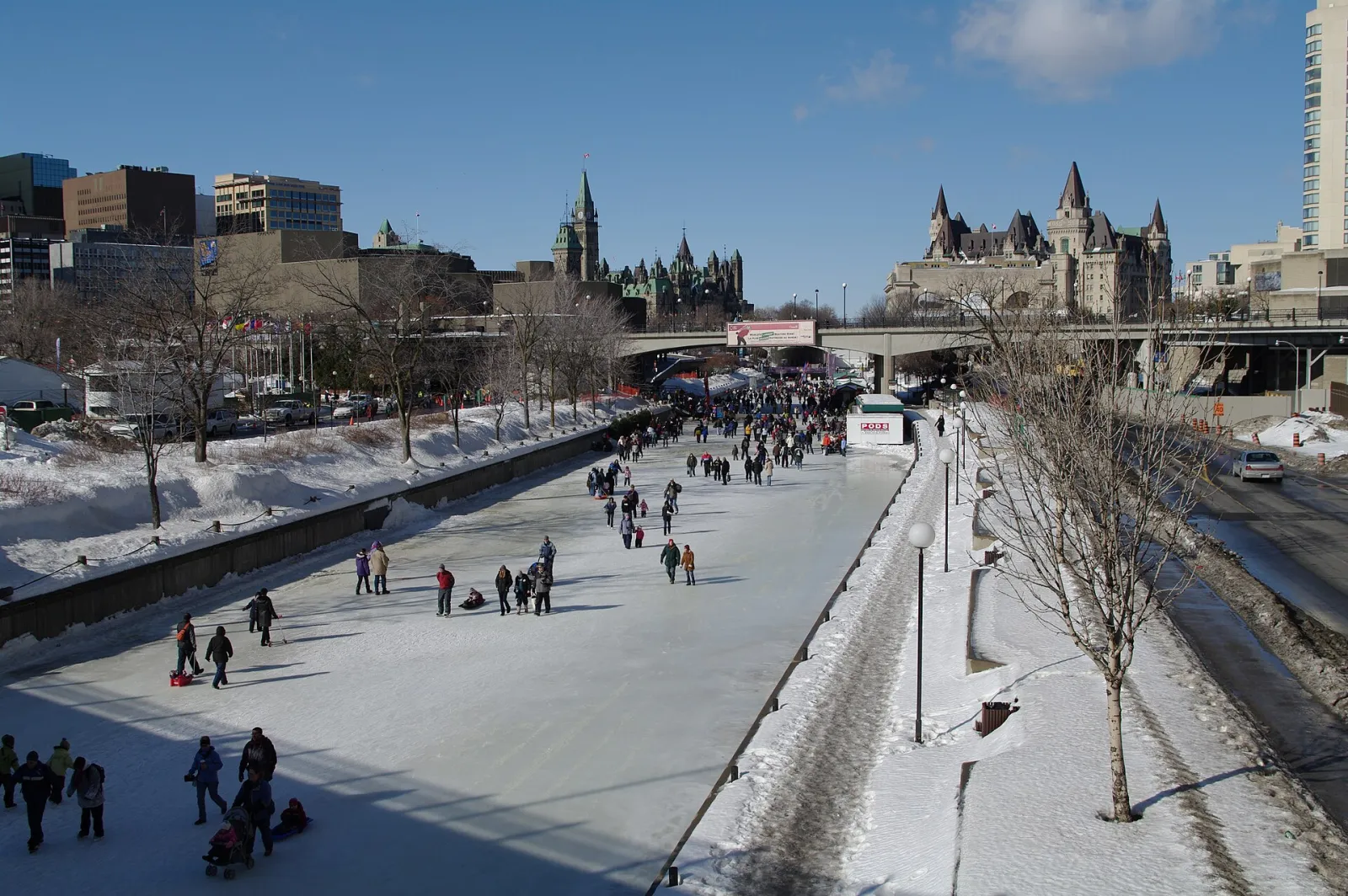 El Rideau Canal Skateway en el centro de Ottawa en un día soleado de invierno, con patinadores sobre el hielo despejado y el Château Laurier y los edificios del Parlamento al fondo — Rideau Canal Skateway
