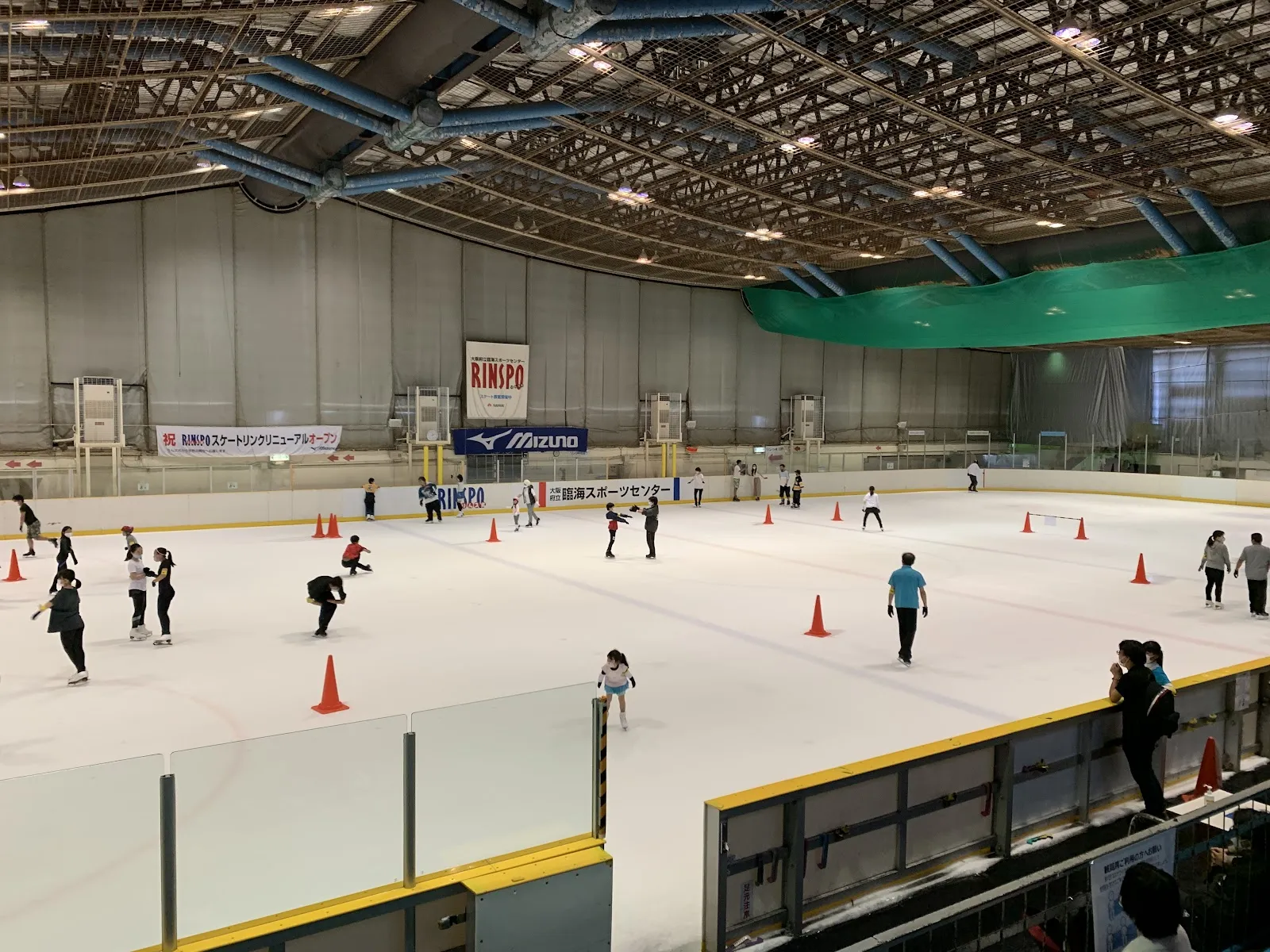 The ice sheet of the Rinkai Sports Center during a public session, seen from the stand with the RINSPO banner on the wall — Osaka Prefectural Rinkai Sports Center (Rinspo)