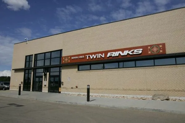 The Twin Rinks building at River Cree Resort: a tan brick wall with large windows and the Twin Rinks lettering under a blue sky. — River Cree Twin Rinks