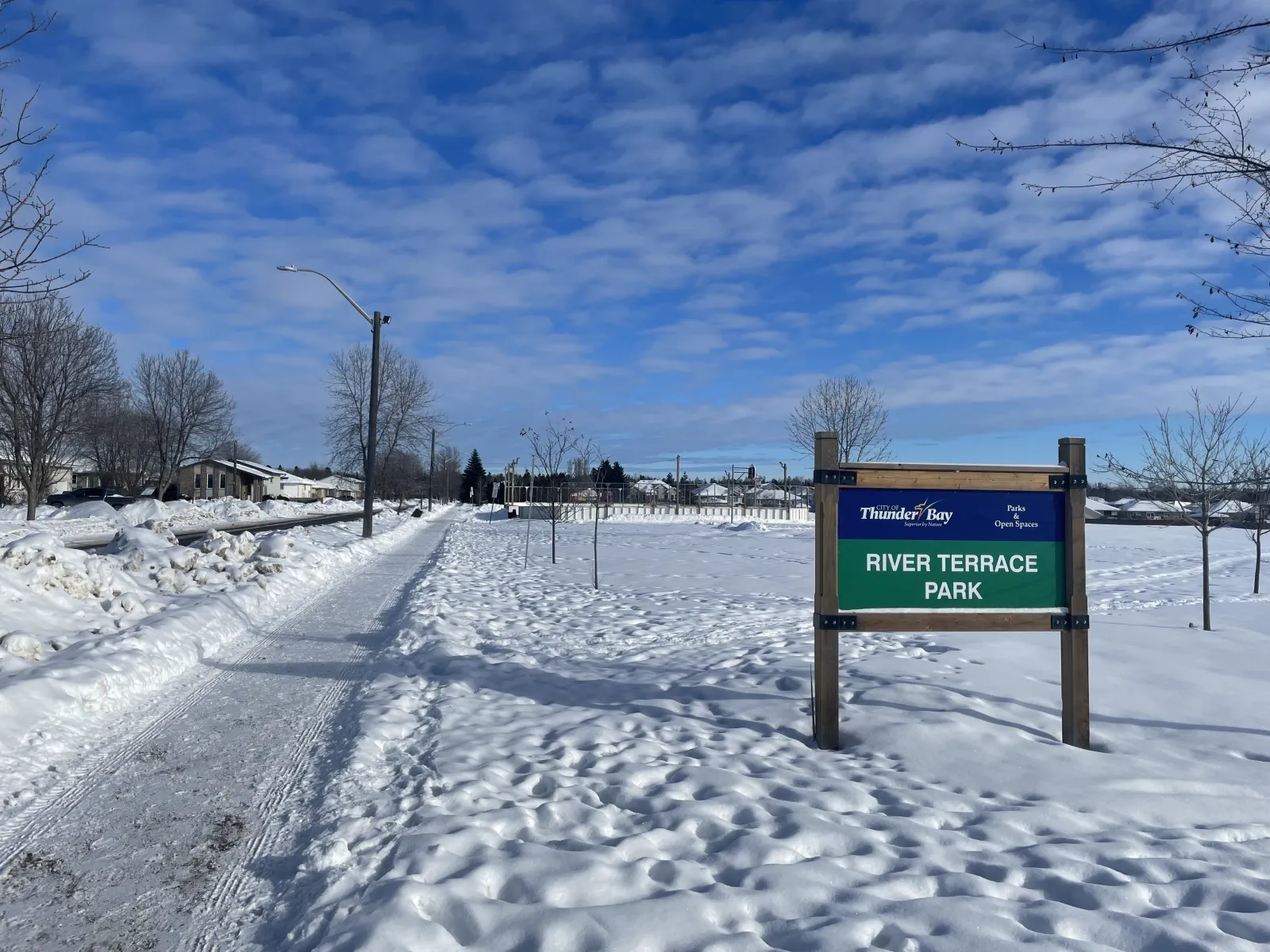 The River Terrace Park sign beside the pathway to the rink — River Terrace Park Outdoor Rink