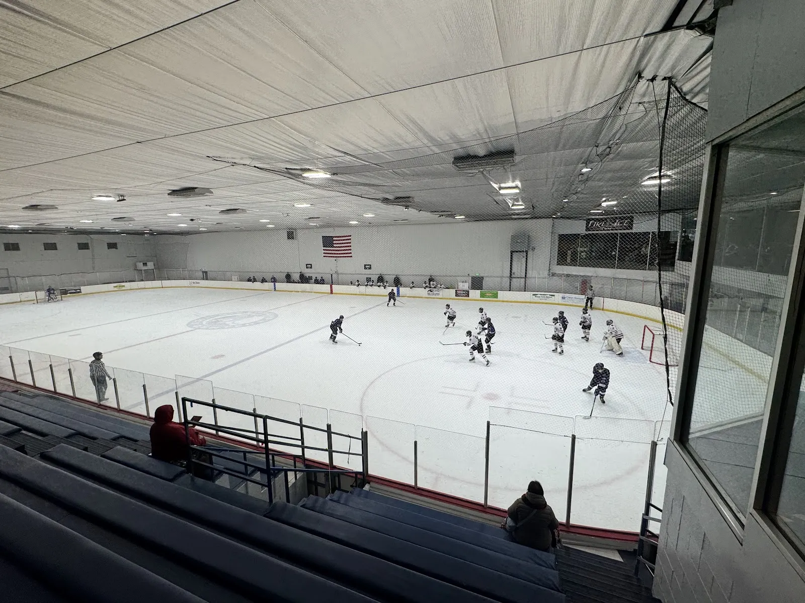 A game on the ice sheet at Riverbend Ice Center seen from the stands, with players at a distance — Riverbend Ice Center
