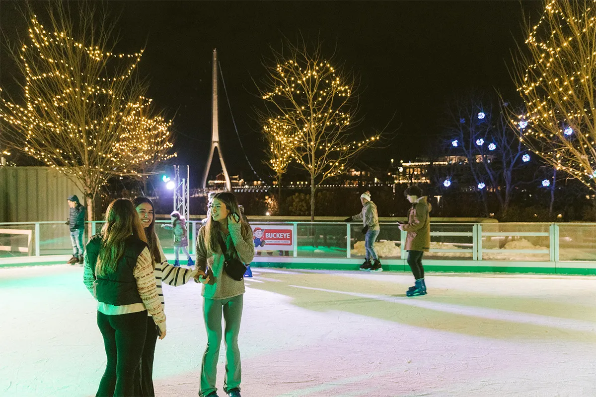Skaters on the Riverside Crossing Park ice at night with the Dublin Link bridge pylon behind — Riverside Crossing Park Ice Rink