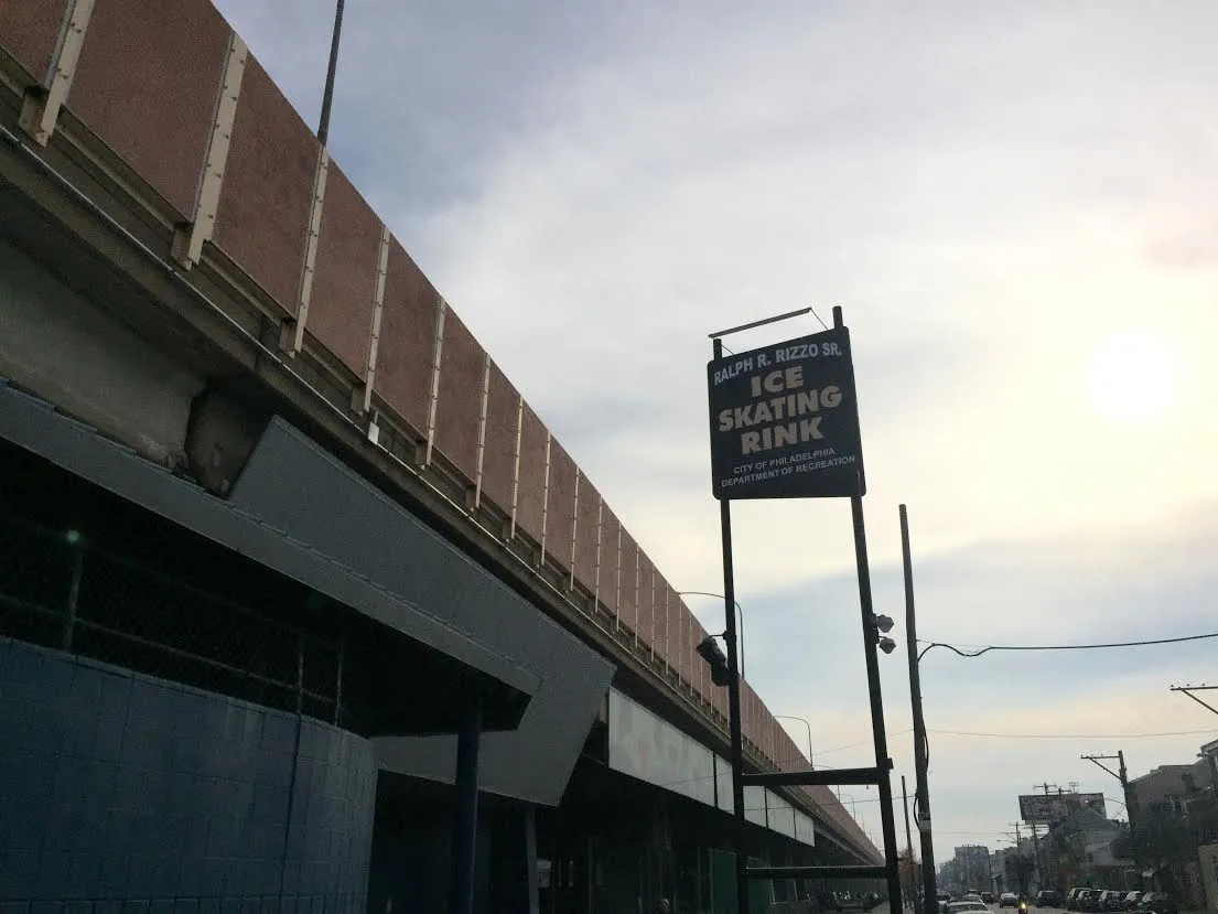 El letrero de la calle de la pista y el muro liso del edificio que corre bajo el paso elevado de la Interstate 95 en South Front Street. — Rizzo Rink