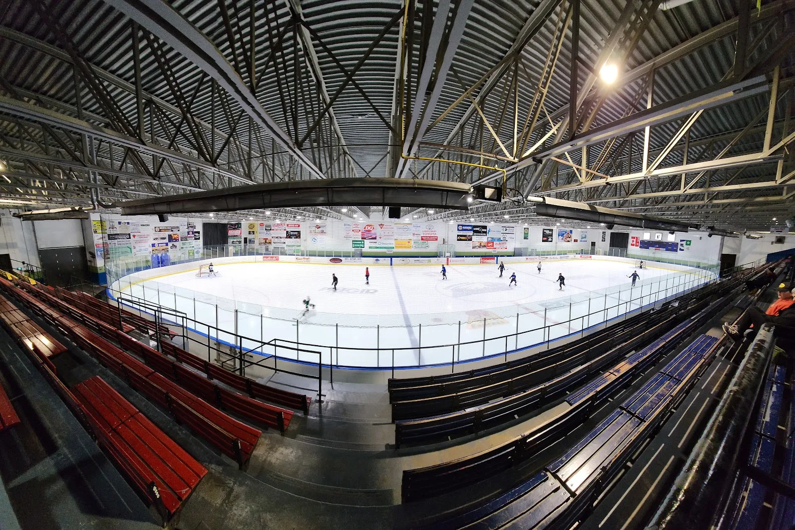 The NHL-size rink from the upper stands during a practice, under the steel roof trusses. — Robert Hartley Sports Complex (Hawkesbury)