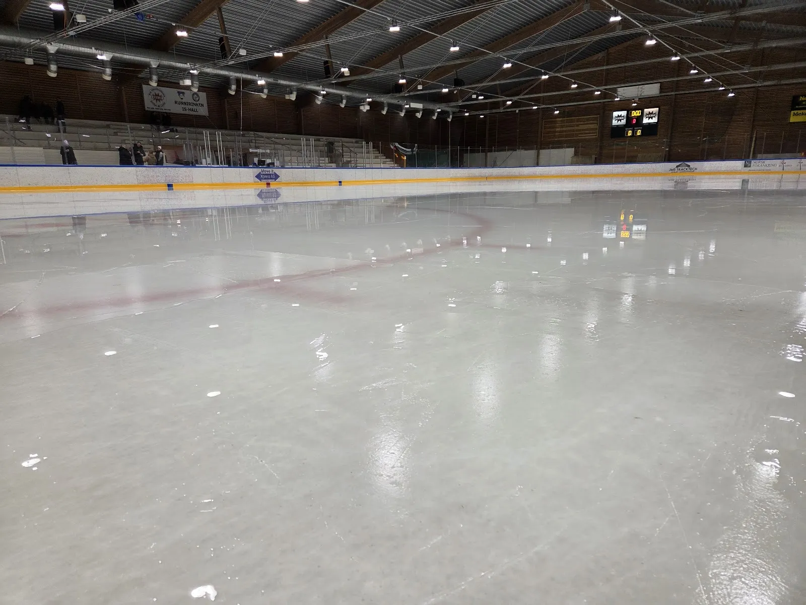 The ice inside Runnirinken ishall with the boards, stands and scoreboard behind a freshly resurfaced sheet. — Runnirinken ishall