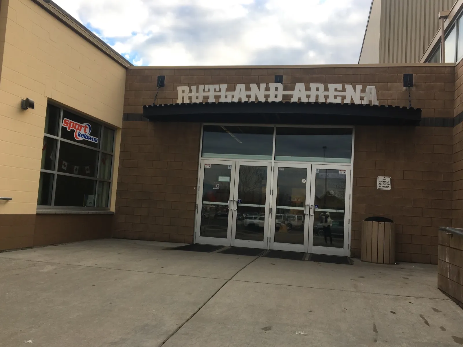The brick entrance with Rutland Arena lettered above the glass doors under a dark awning, and a concrete plaza in front. — Rutland Arena
