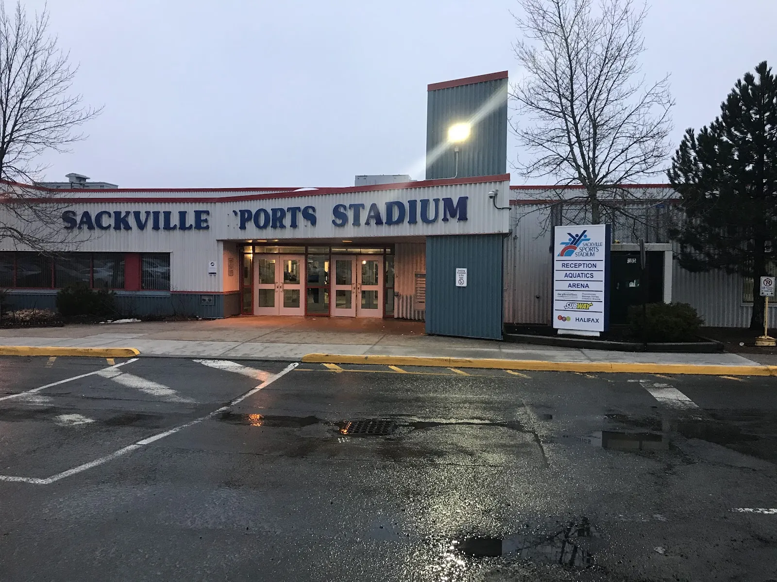 The front entrance of the Sackville Sports Stadium in Lower Sackville, with its name across the facade and the parking lot in front. — Sackville Sports Stadium