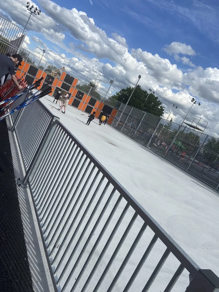 The outdoor rink area beside the Scanlon recreation building, seen past the railing on a bright day. — Scanlon Ice Rink