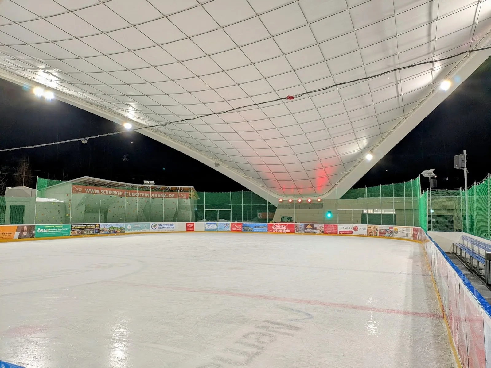 The ice surface of the Schierker Feuerstein Arena under its roof, lit from above, seen from the side of the rink. — Schierker Feuerstein Arena
