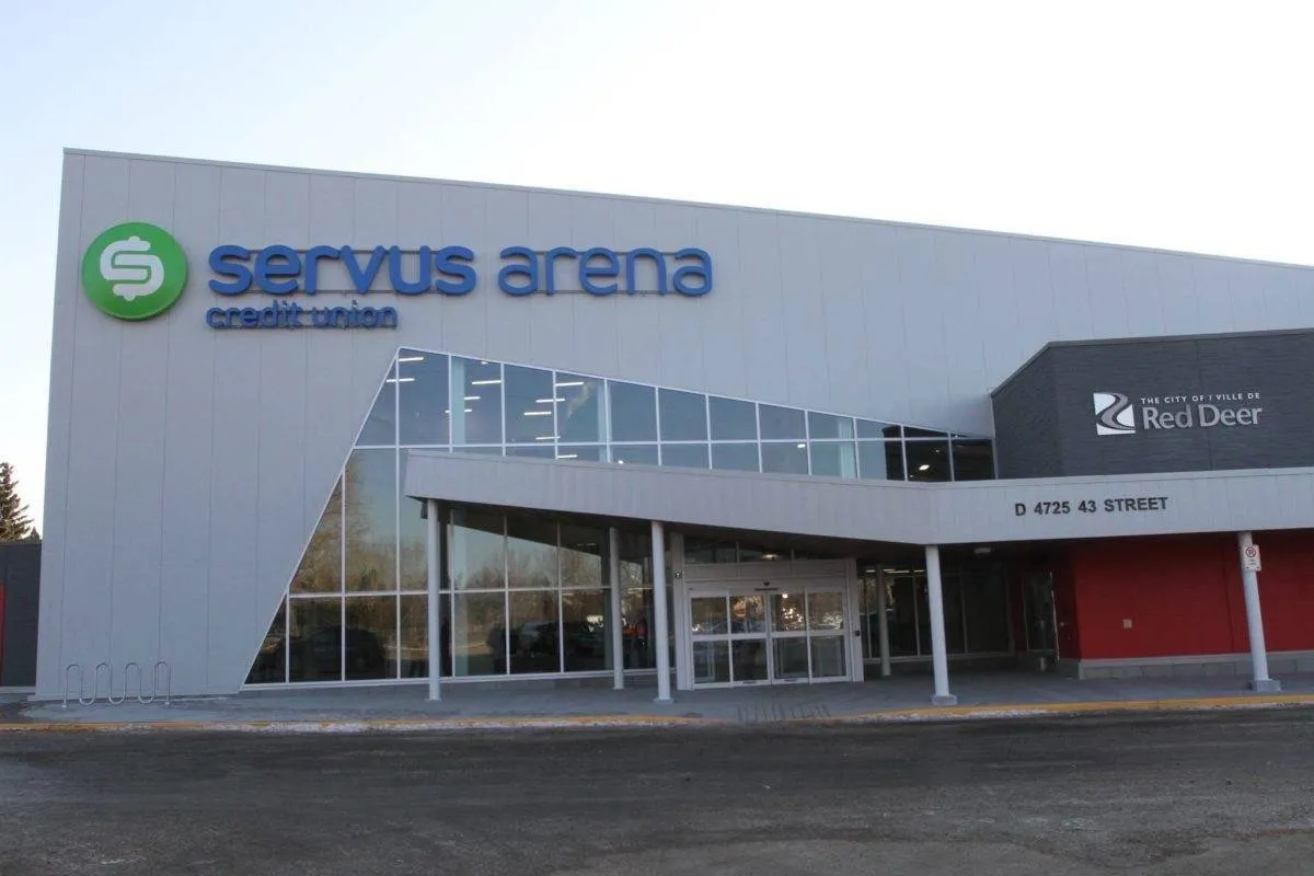 The white-clad arena with the green Servus Arena credit union sign above a glass entrance on 43 Street. — Servus Arena
