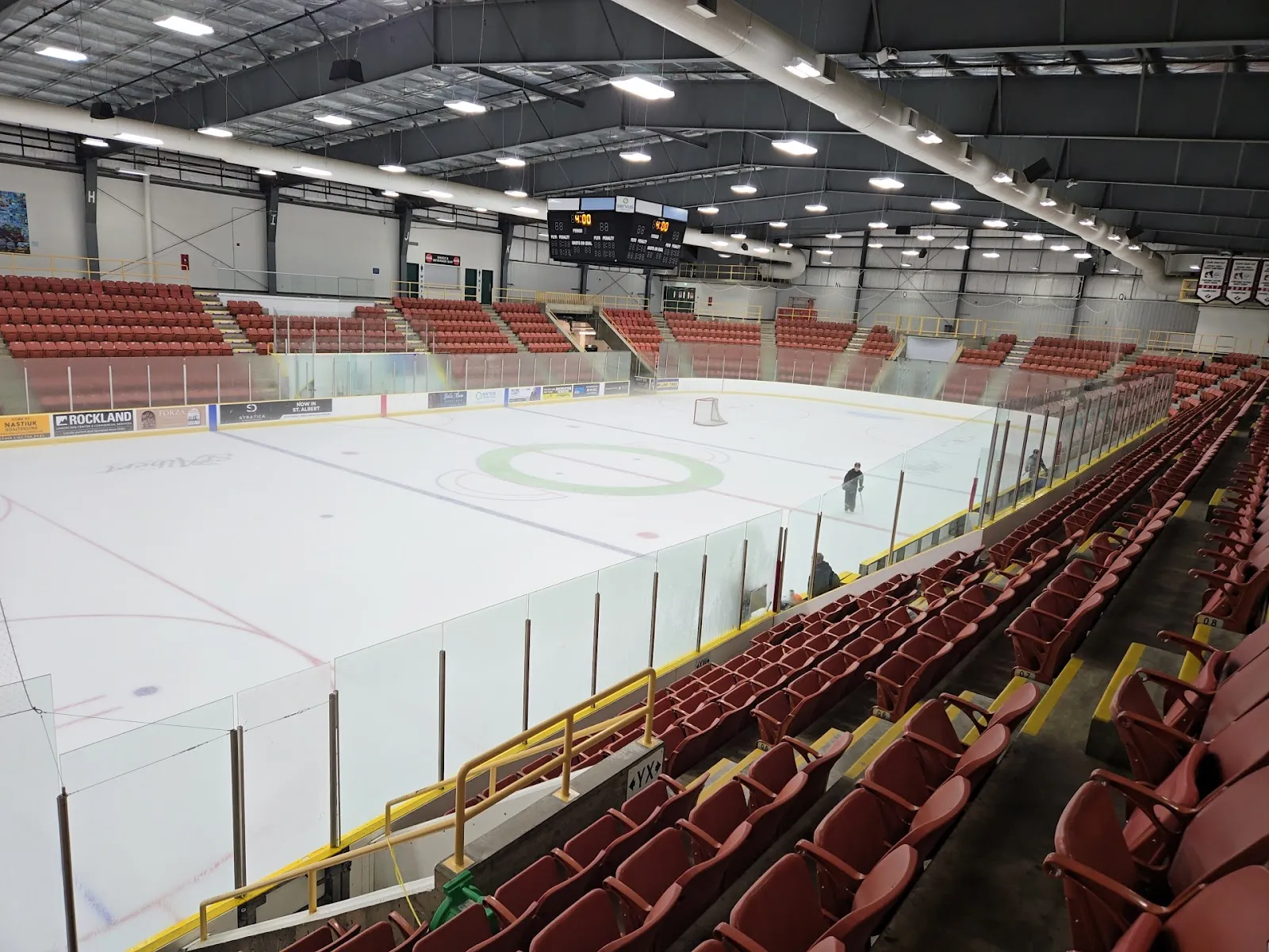 The Performance Arena's empty sheet below rows of red seats, with the scoreboard hung at the far end. — Servus Credit Union Place