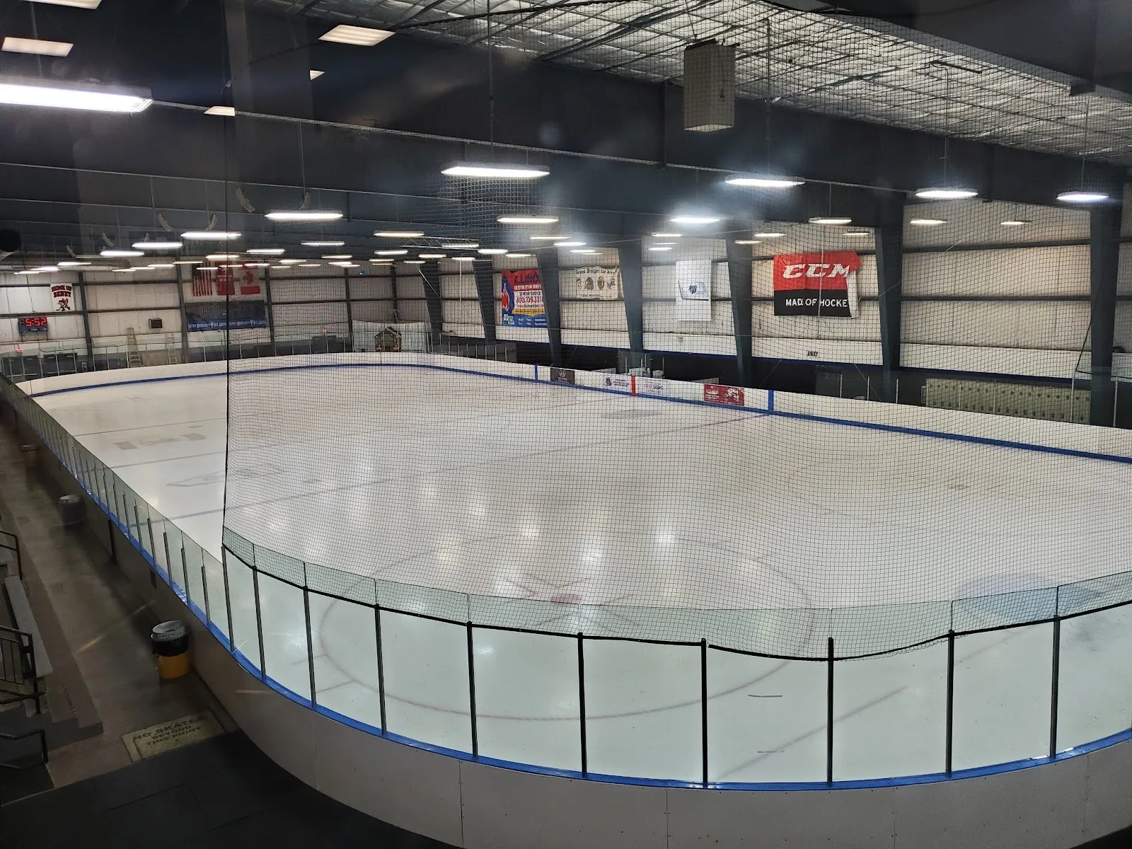 The empty ice at the Seven Bridges Ice Arena in Woodridge, seen from above the boards through the end netting — Seven Bridges Ice Arena
