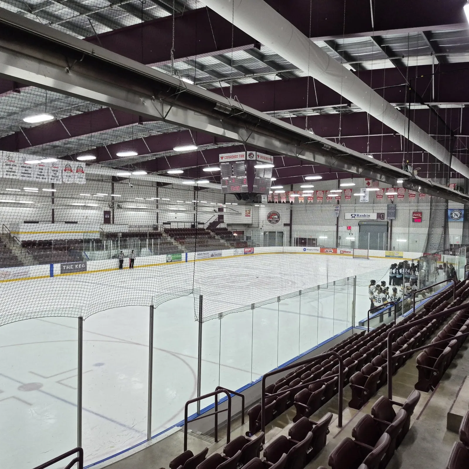 El hielo del Seymour-Hannah Sports and Entertainment Centre visto desde las gradas, con asientos color guinda, armaduras de acero en el techo y mantas en el muro del fondo — Seymour-Hannah Sports and Entertainment Centre