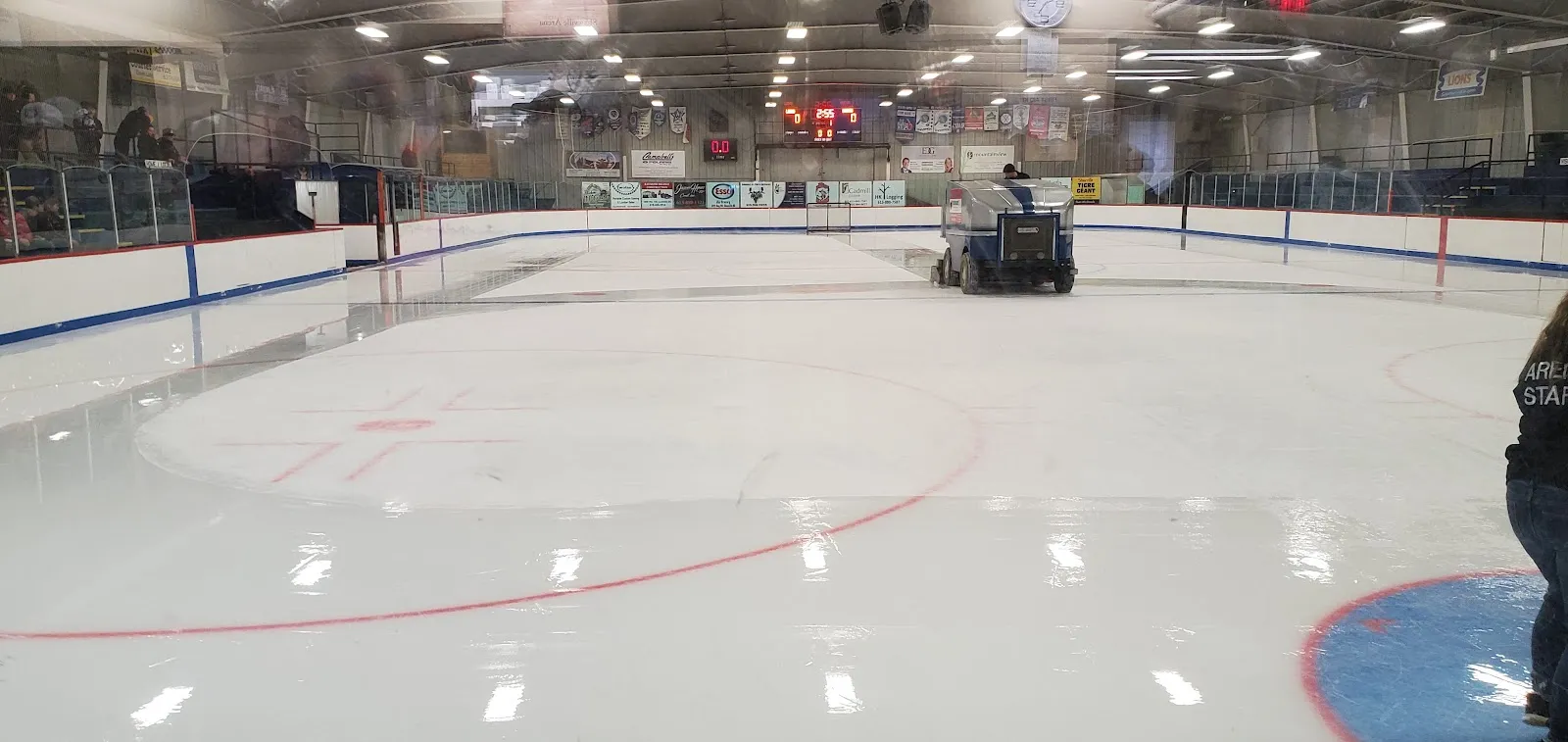 The freshly resurfaced ice of the Shawville Arena with the ice resurfacer at the far end, the boards and the scoreboard — Shawville Arena