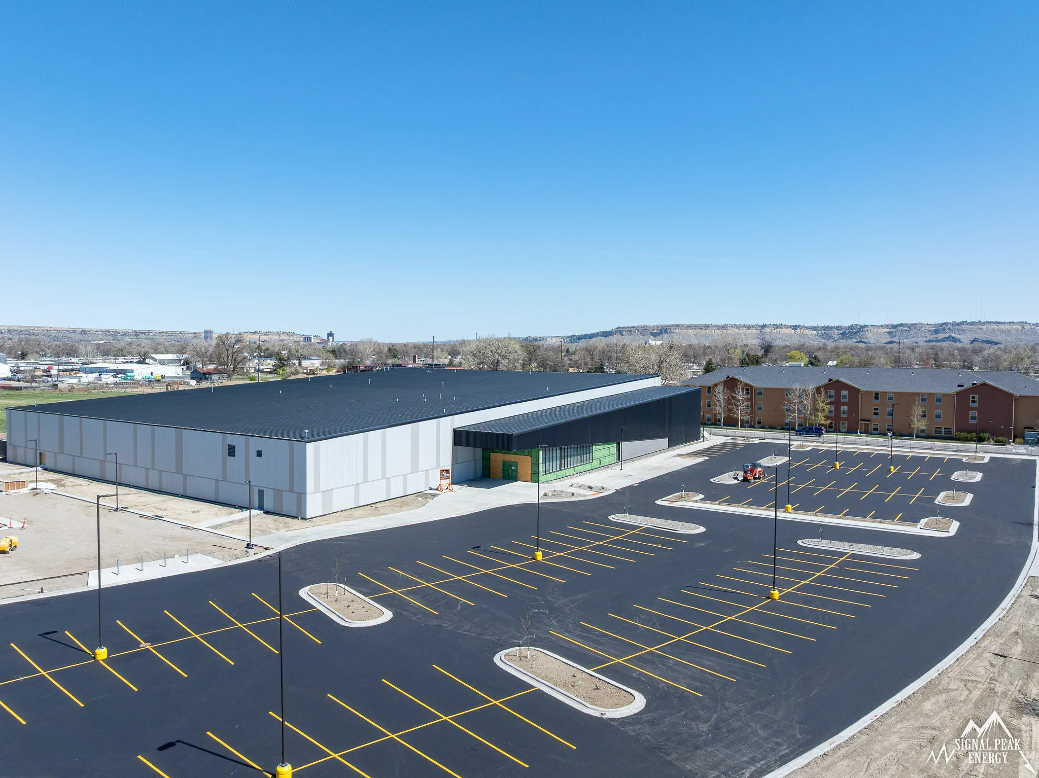 Long white metal arena building with its dark standing-seam roof — Signal Peak Energy Ice Arena