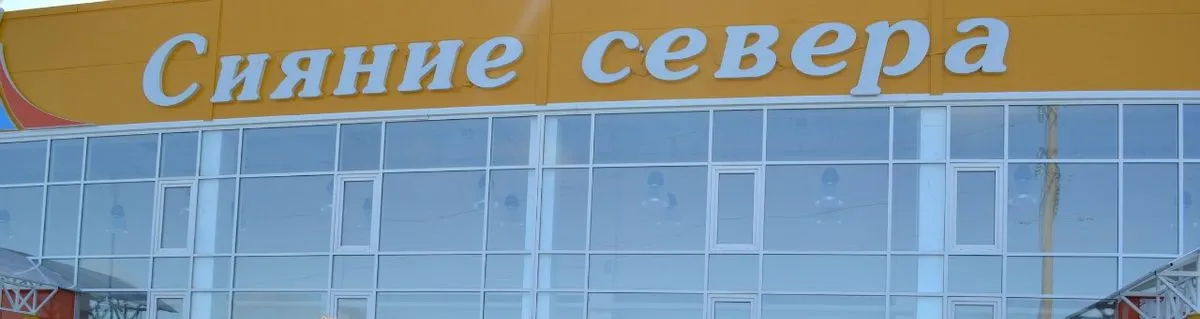 Жёлтая вывеска и стеклянный фасад ледового дворца «Сияние севера» в Печоре — Siyanie Severa Ice Palace Pechora