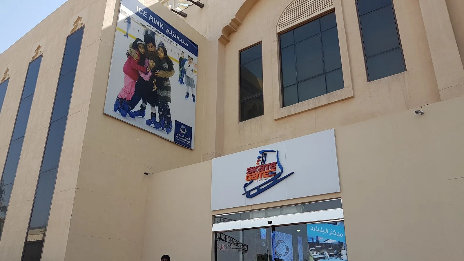 مدخل «سكيت غيت» ولافتته على الجدار ذي لون الحجر الرملي في قرية الشعب — Skate Gate Ice Rink
