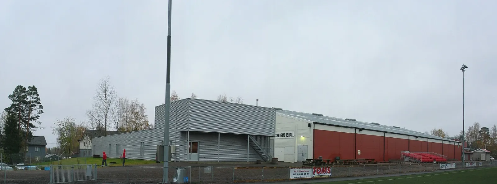Skedsmo Ishall seen from the football pitch: the long hall with its red and grey walls. — Skedsmo Ishall