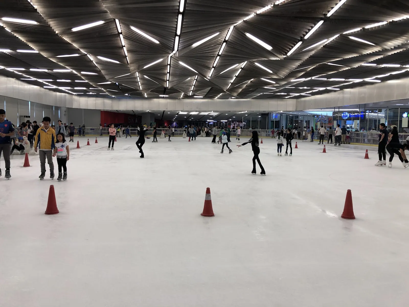 The sheet at SM Skating Megamall under its ceiling of light strips, with traffic cones and skaters on the ice. — SM Skating Megamall
