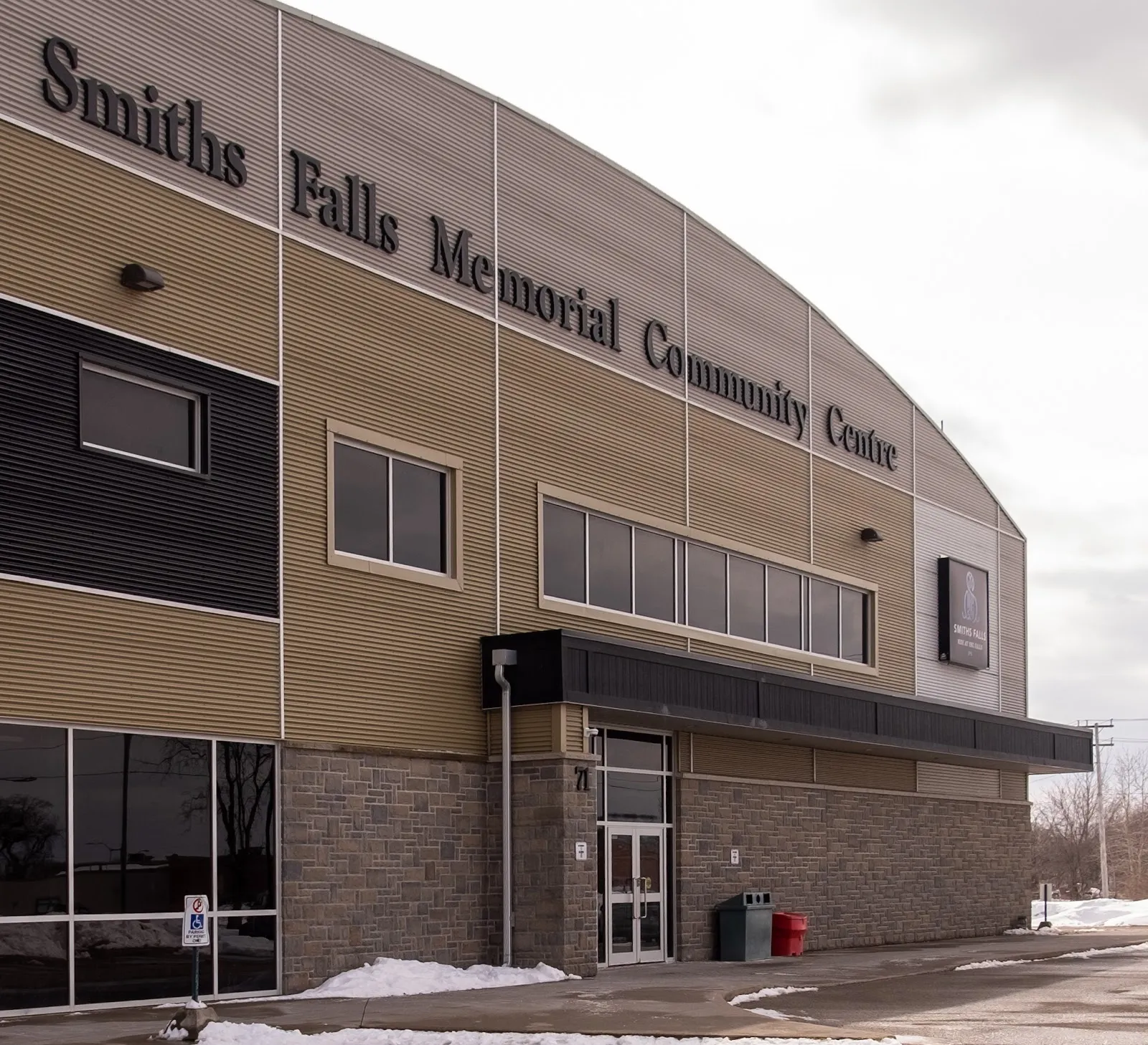 The curved front of Smiths Falls Memorial Community Centre, with its name in large letters along the wall above the entrance — Smiths Falls Memorial Community Centre