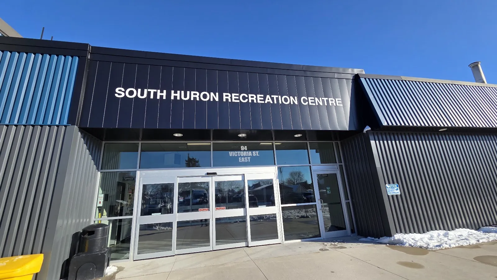 La entrada renovada en azul marino y gris de South Huron Recreation Centre, con puertas automáticas de vidrio. — South Huron Recreation Centre (Exeter)