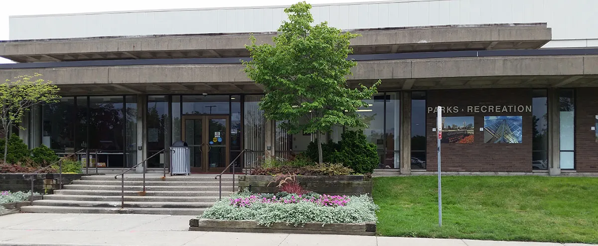 La entrada de ladrillo y vidrio del Parks & Recreation Building en 26000 Evergreen Road, la dirección que la ciudad da para el Southfield Sports Arena, con escalones de concreto y jardineras al frente. — Southfield Sports Arena