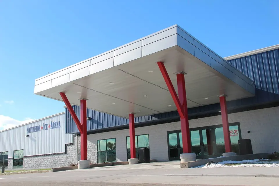 The building's front entrance canopy with red support columns and Southside Ice Arena signage on the wall, daytime. — Southside Ice Arena