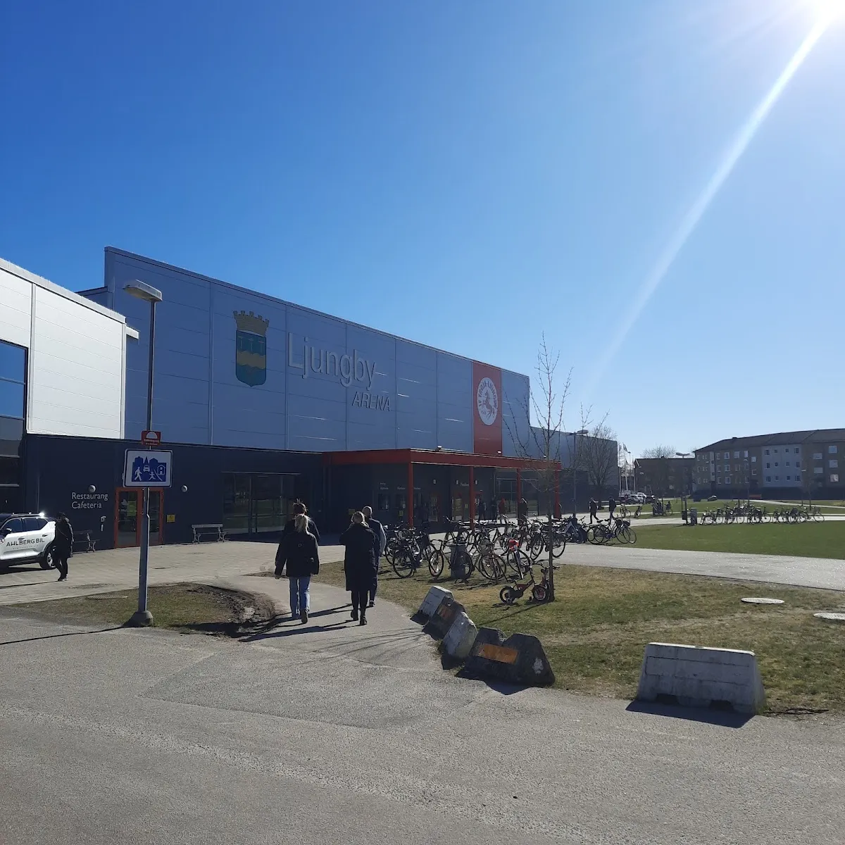 The front of Ljungby Arena with the town crest on its blue-grey wall and bicycles outside – SP Arena (ishallarna), Ljungby