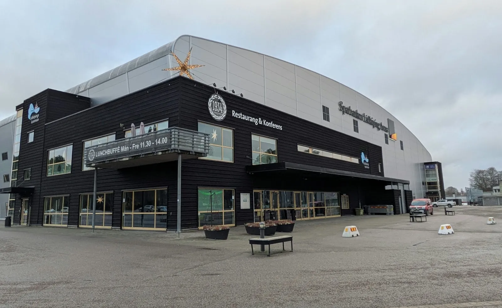 The dark timber-clad entrance of Sparbanken Lidköping Arena under its curved silver-metallic roof — Sparbanken Lidköping Arena
