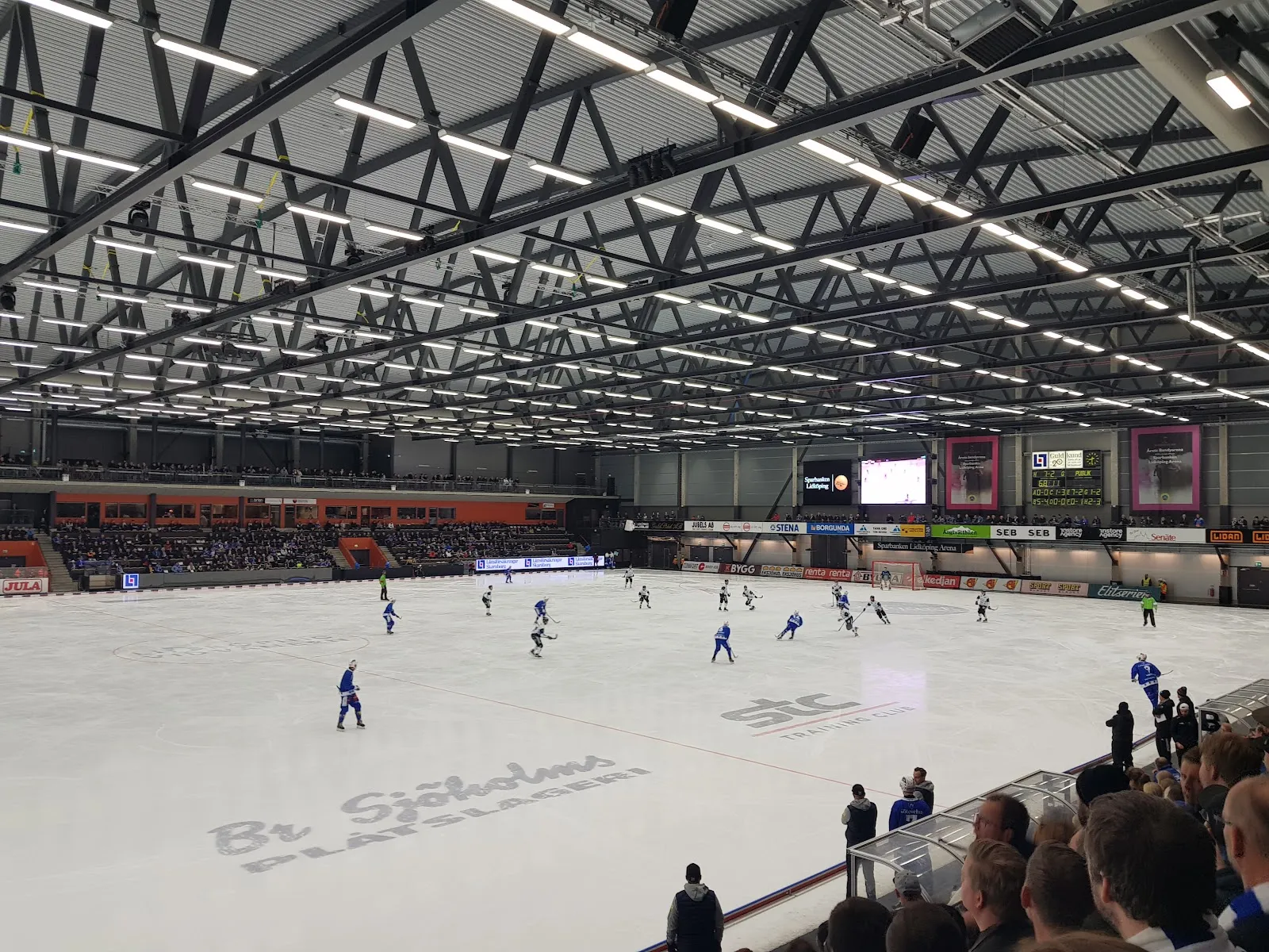 A bandy game on the large ice of Sparbanken Lidköping Arena under the steel roof trusses — Sparbanken Lidköping Arena