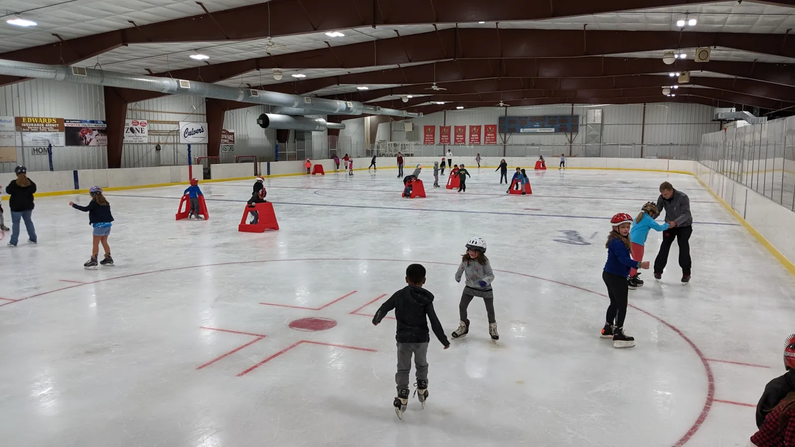 Un patinaje público en la arena de Sparta: patinadores de todas las edades repartidos por el hielo, con conos colocados y vigas oscuras en el techo. — Sparta Hockey Arena