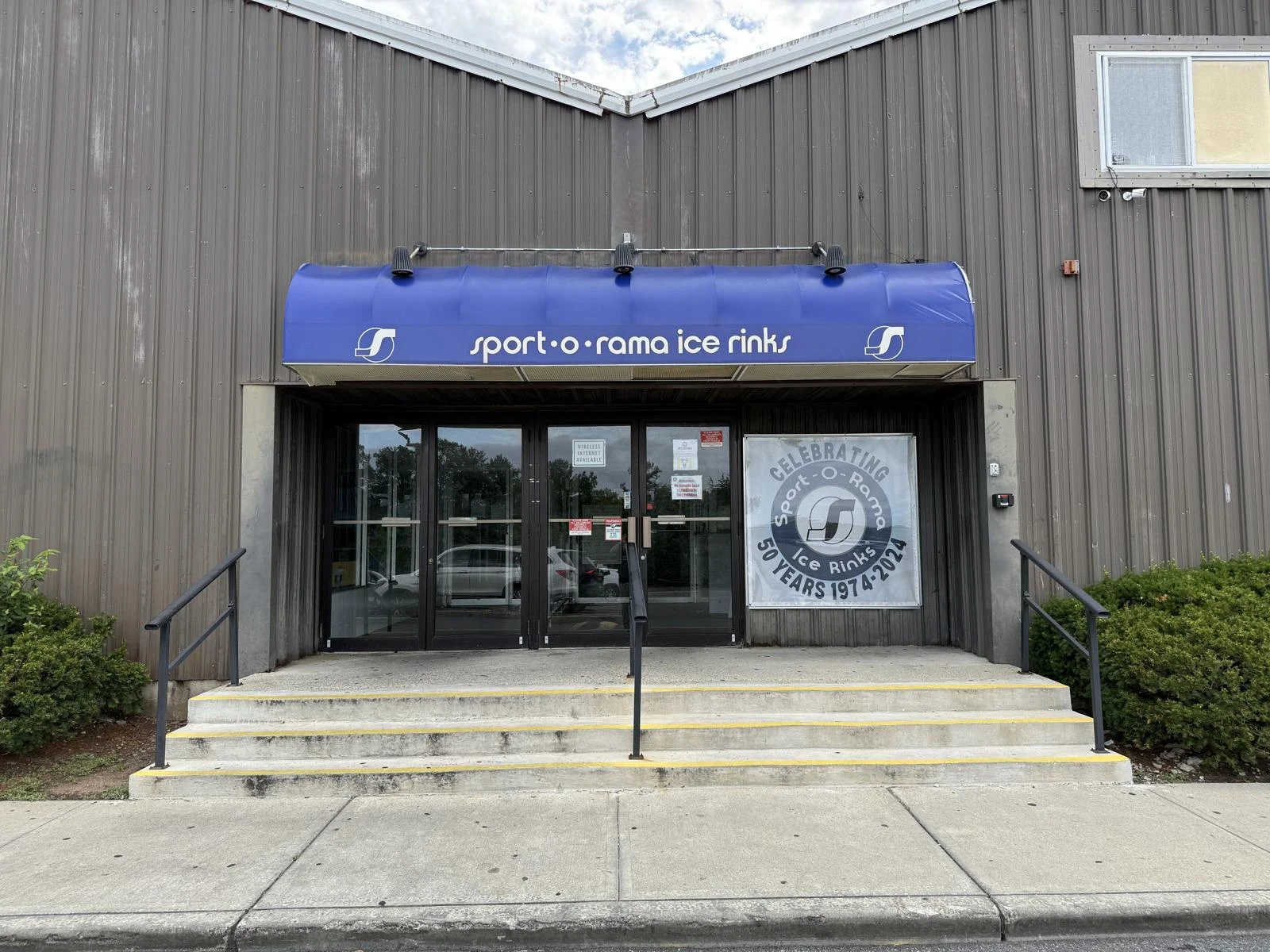 Sport-O-Rama’s front steps and entrance beneath its blue arena awning. — Sport-O-Rama Ice Rinks
