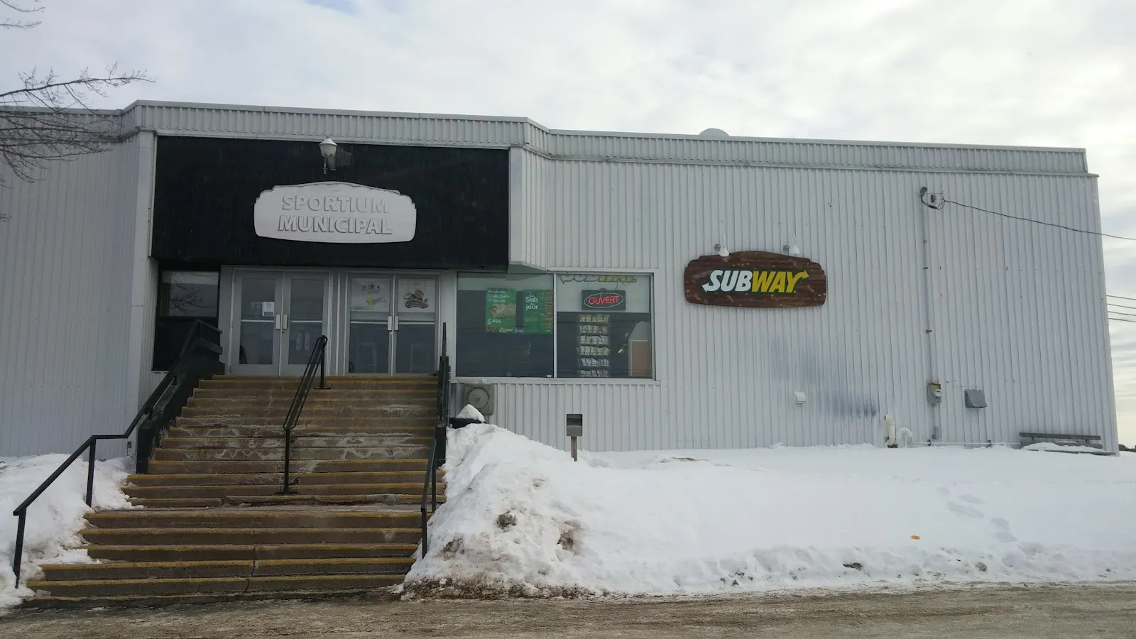 La façade du Sportium municipal (aréna) en hiver, avec son nom au-dessus de la porte. — Sportium municipal