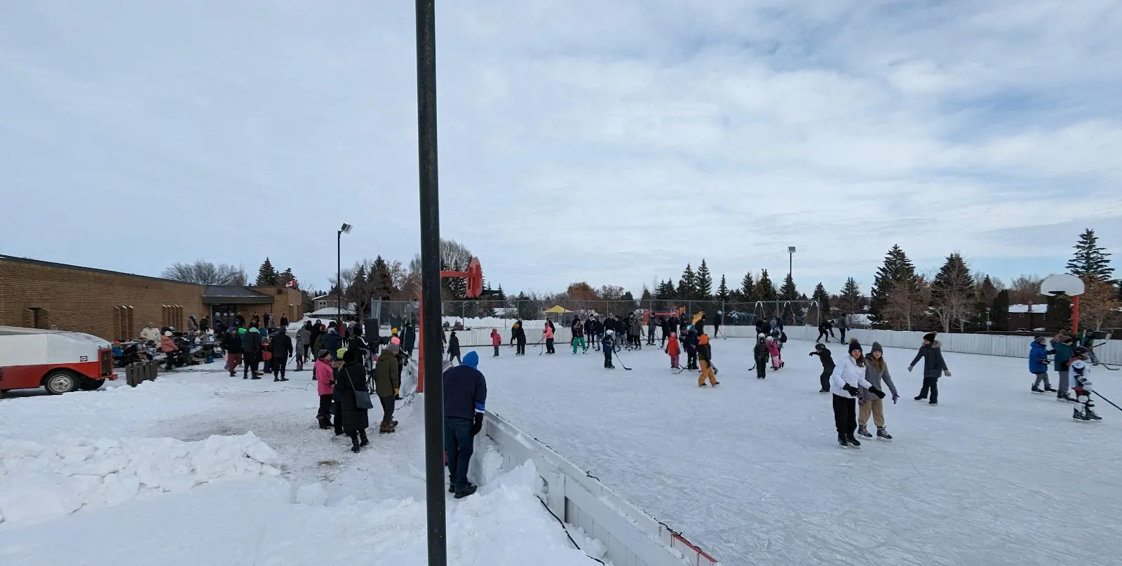 Patinaje público en la pista al aire libre de St. George School con la escuela detrás (foto del listado de Google Maps) — St. George School Outdoor Rink (Lawson Heights)