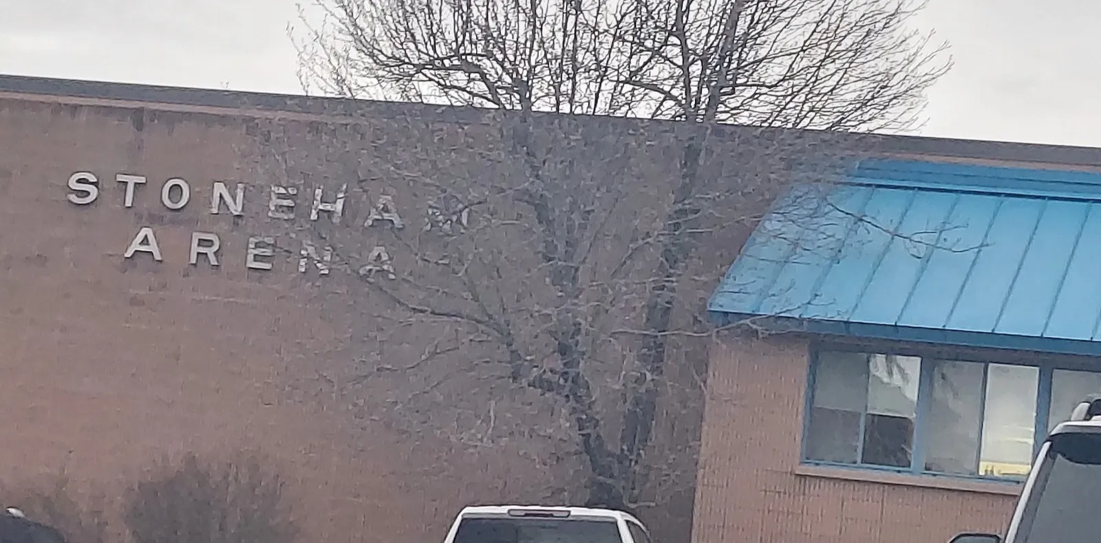 Stoneham Arena's brick wall with its STONEHAM ARENA lettering, beside the blue metal roof over the entrance wing on Montvale Avenue — Stoneham Arena