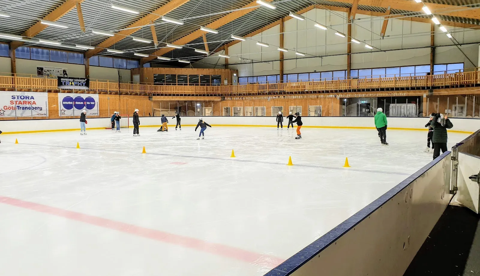 Public skaters on the ice at Stora Mossens ishallar, under the timber-framed roof — Stora Mossens ishallar