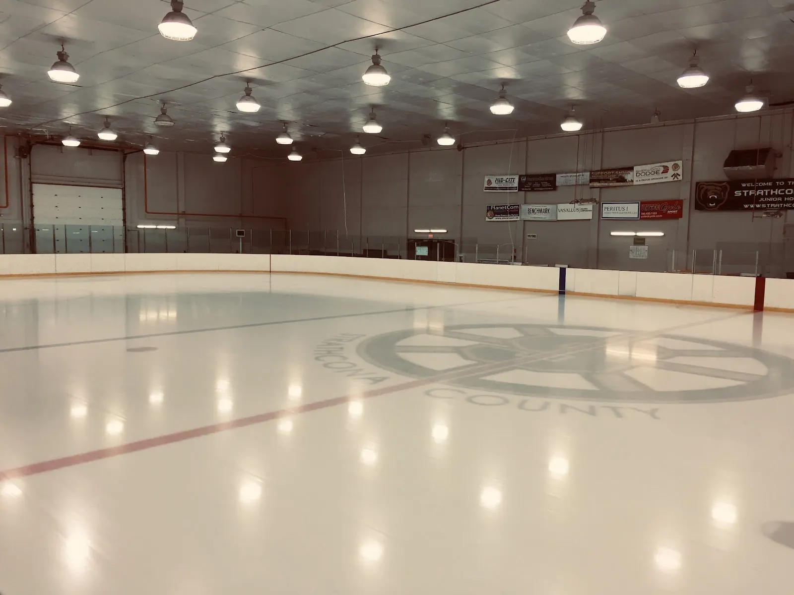 The empty Olympiette ice, freshly flooded, with the Strathcona County crest painted at centre. — Strathcona Olympiette Centre