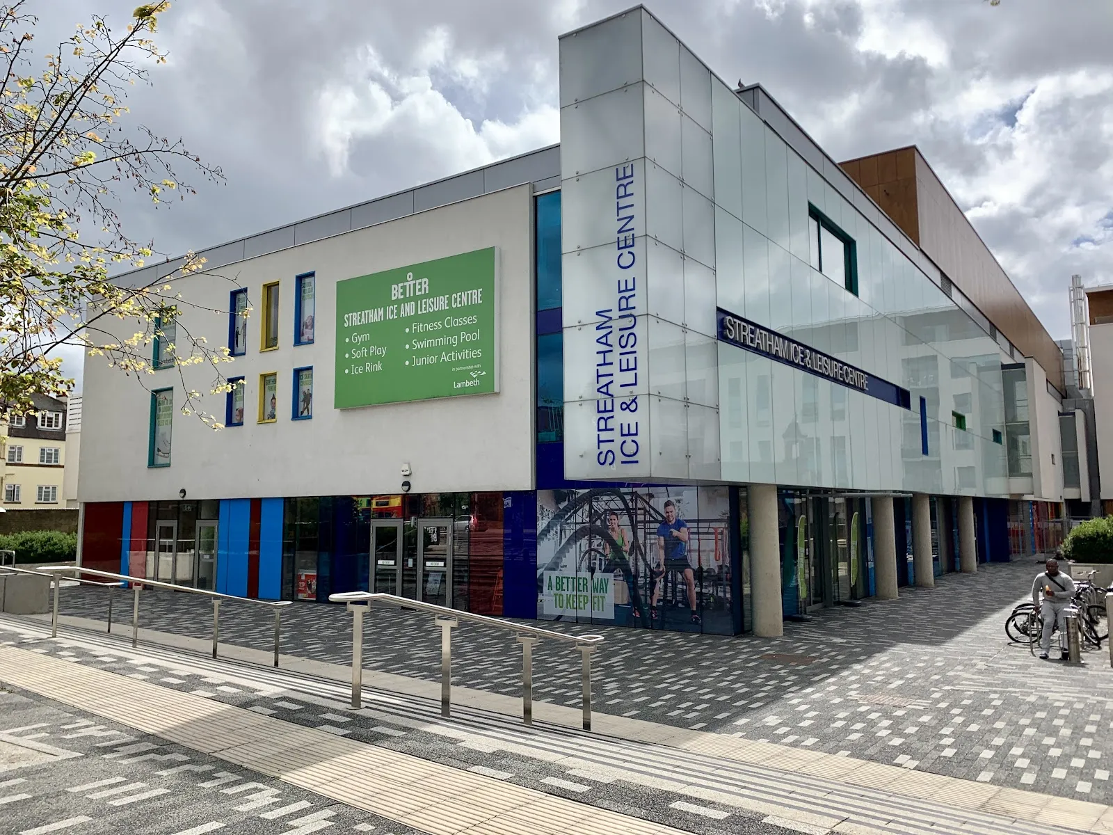 The white and glass front of the centre in daylight, with 'Streatham Ice & Leisure Centre' lettering down the tower and a green Better sign above the ground-floor entrances. — Streatham Ice and Leisure Centre