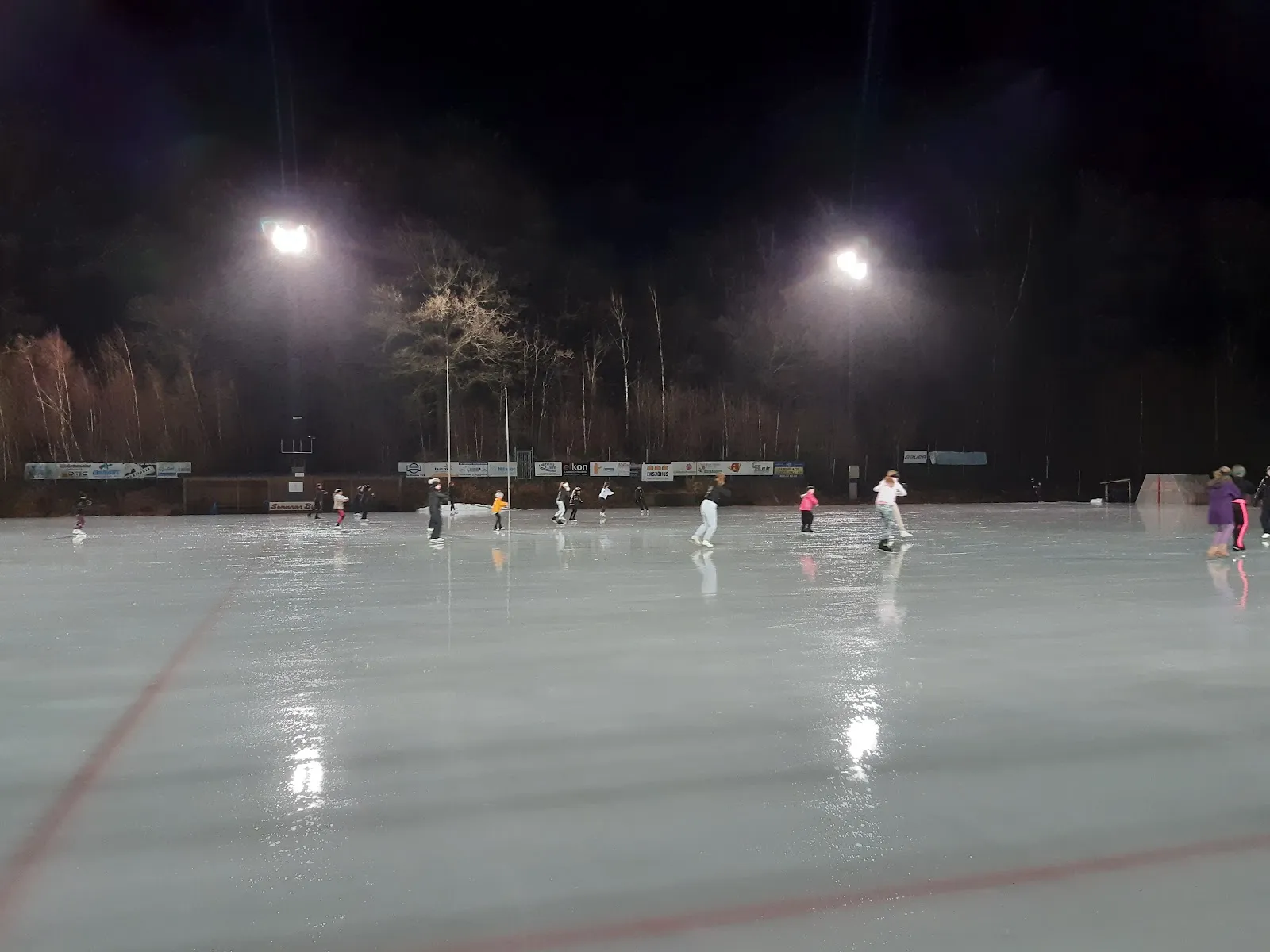Skridskoåkare på den upplysta isen vid Strömvallens isbana i Oskarström en kväll – Strömvallens isbana
