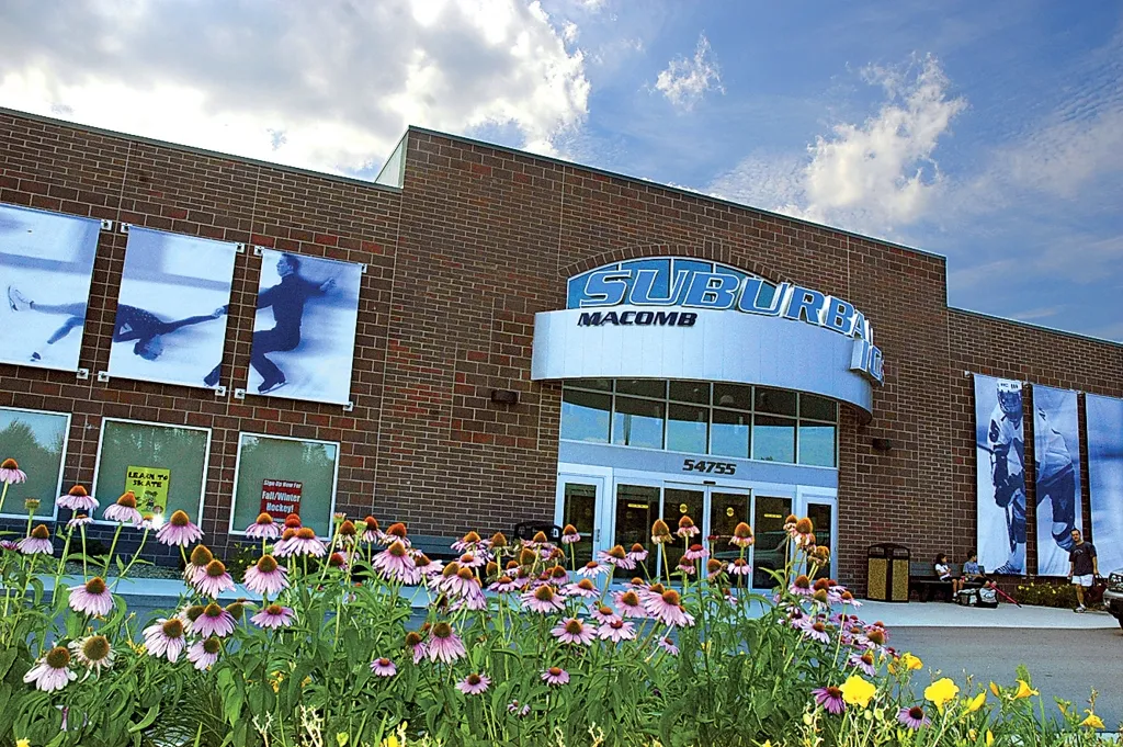 Brick front entrance with large 'Suburban Ice Macomb' sign above the doors at 54755, coneflowers in the foreground. — Suburban Ice Macomb