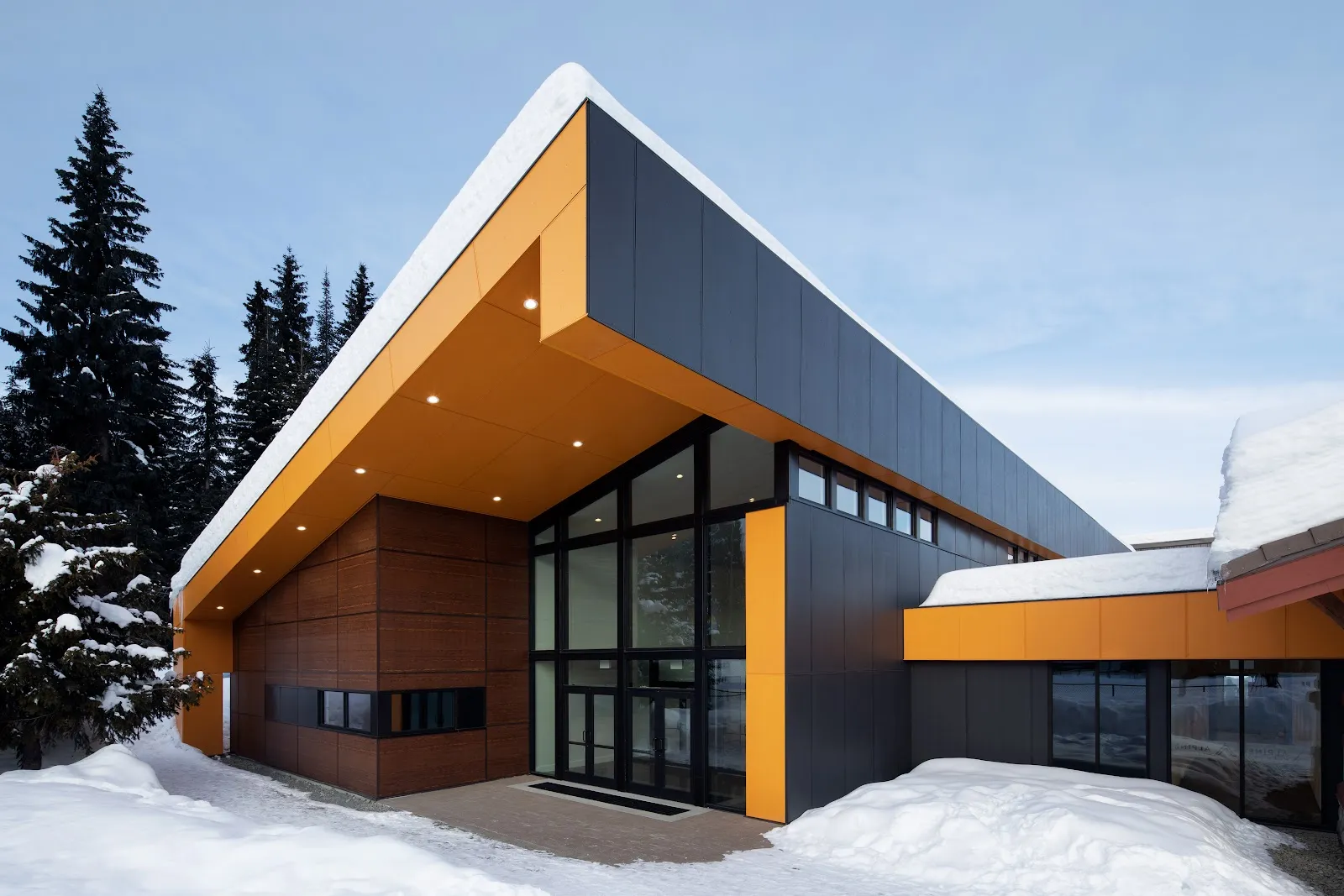 The Sun Peaks Centre building in winter, with its orange-trimmed roofline and snow — Sun Peaks Arena (Sun Peaks Centre)